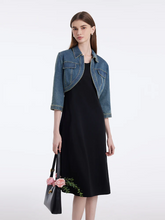 a lady in a denim crop jacket and black vest dress